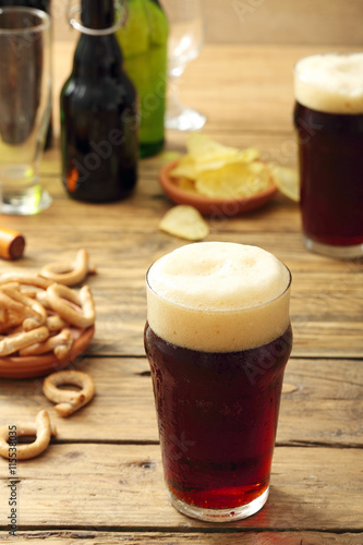 Fotografie bicchiere di  birra scura su sfondo tavolo di legno rustico