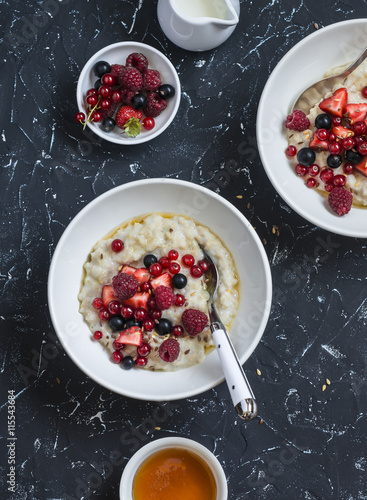 Oatmeal with berries and honey on a dark background. Healthy breakfast