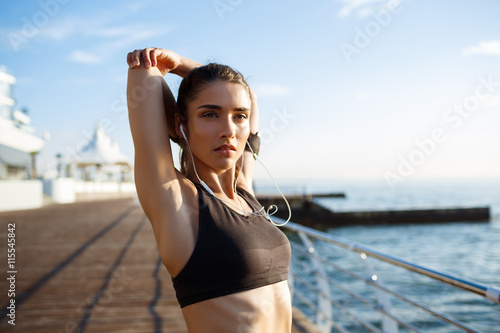 Fototapeta Naklejka Na Ścianę i Meble -  Picture of young beautiful fitness girl makes sport exercises with sea coast on background
