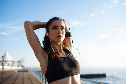 Obraz na plátně Picture of young beautiful fitness girl makes sport exercises with sea coast on