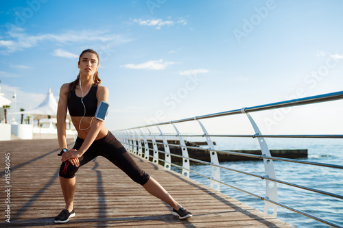 Picture of young fitness girl who makes sport exercises with sea coast on background