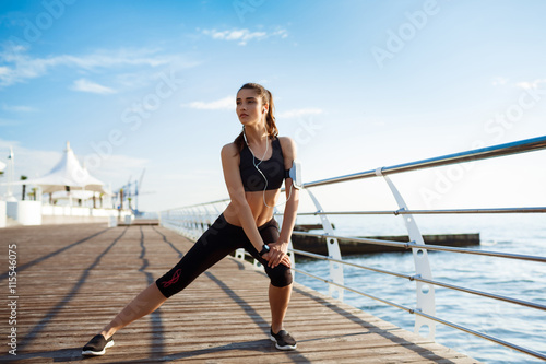Picture of young fitness girl who makes sport exercises with sea coast on background