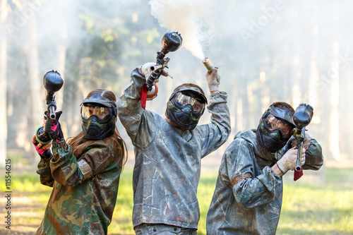 Company of friends posing with smoke grenade and paintball guns