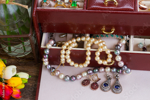 Jewellery in treasure box with fresh fresia flowers on desktop