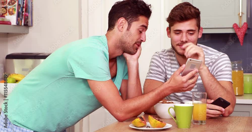 Friends laughing while using smartphones in the kitchen Friends laughing while using smartphones in the kitchen
