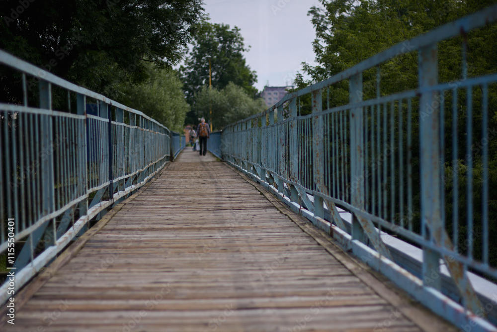 Obraz premium View along a long old footbridge with railings on either side