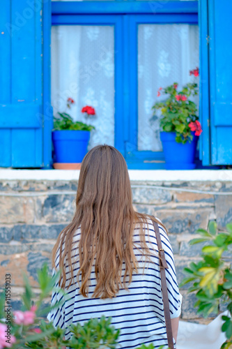 Young girl with long hair standing near the window blue flowers © smoskvitin