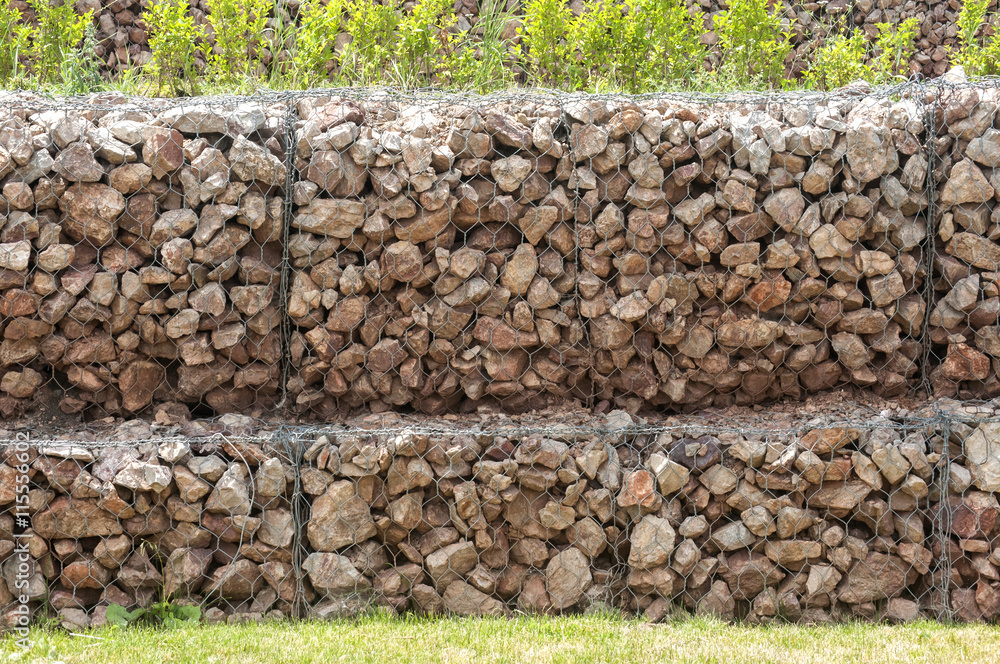 Hexagonal wire netting gabion box wall filled with stones closeup as background