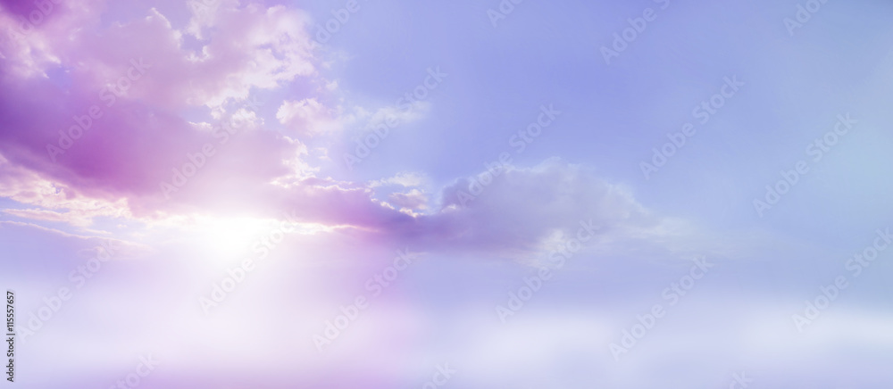 Romantic Lilac Sky scape - beautiful wide lilac and pink clouds lue sky and cloud scape with a burst of sunlight emerging from under the cloud base with plenty of copy space