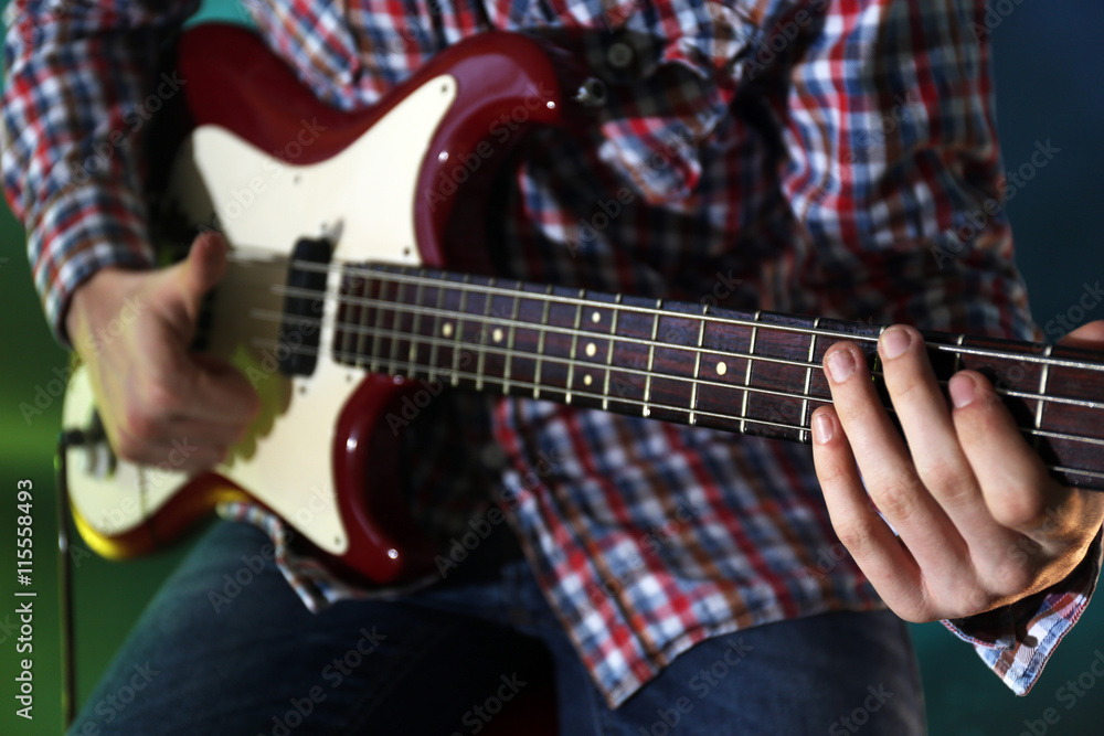 Obraz premium Young man playing electric guitar on lighted dark background