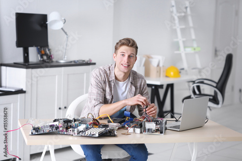 Young man repairing computer hardware in service center
