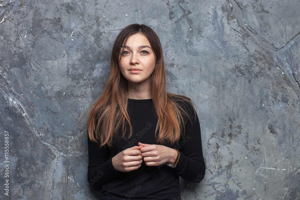 Bright fashion portrait of pretty brunette woman wearing casual outfit posing on urban grey textured background Bright fashion portrait of pretty brunette woman wearing casual outfit posing on urban grey textured background