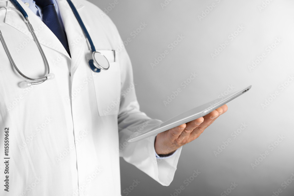 Professional doctor with tablet on grey background Professional doctor with tablet on grey background
