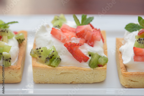 Tarts with whipped cream and strawberries and mint leaves