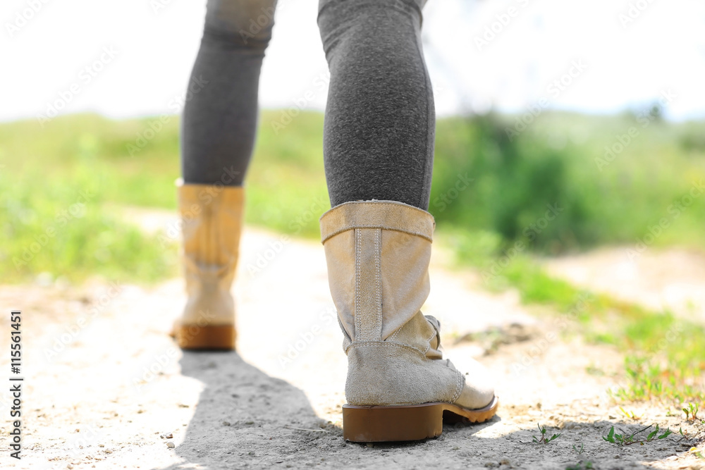Back view of female hiker legs with boots going up the hill at sunny day
