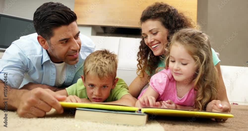 Siblings lying on floor reading book with parents Siblings lying on floor reading book with parents
