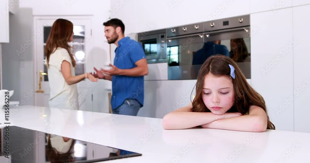 Sad girl looking down while parents are arguing Sad girl looking down while parents are arguing