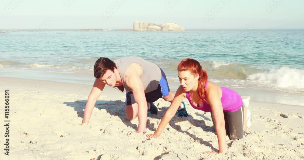 Smiling couple doing push ups at the beach Smiling couple doing push ups at the beach