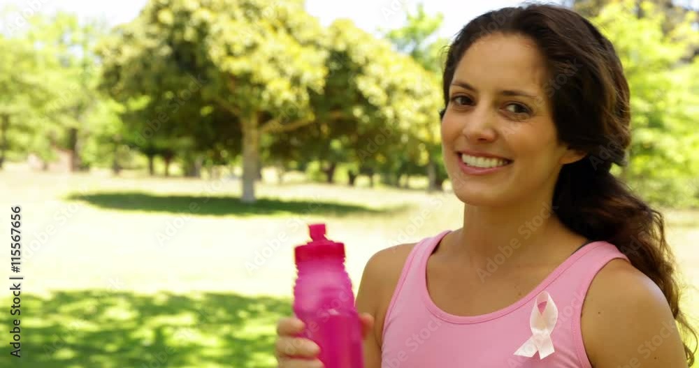 Happy woman wearing pink for breast cancer awareness drinking water Happy woman wearing pink for breast cancer awareness drinking water