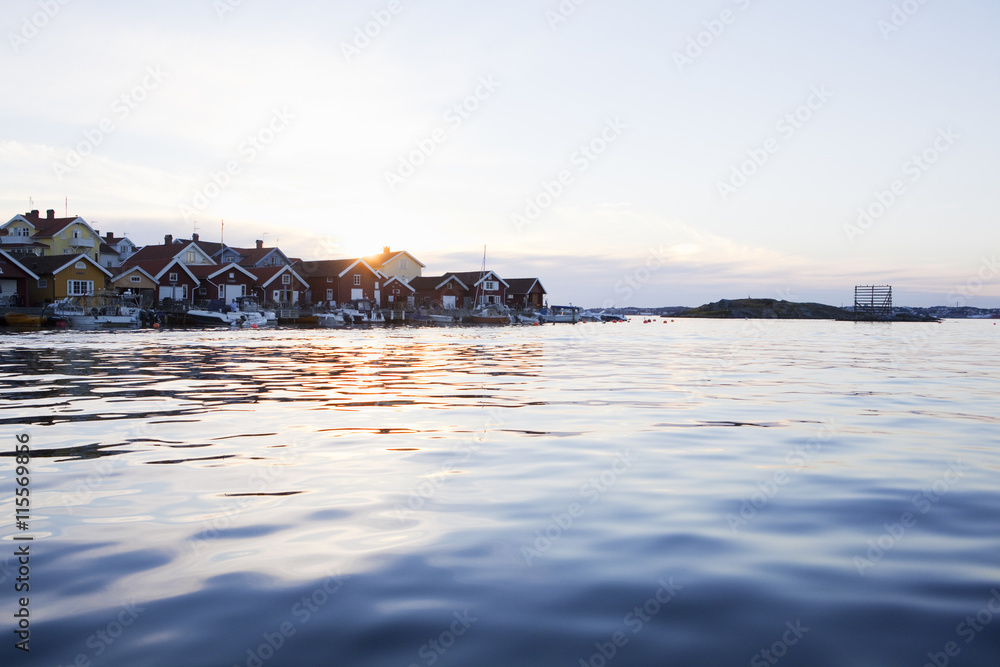 Sweden, Bohuslan, Skafto, Houses and motorboats by sea at sunset Sweden, Bohuslan, Skafto, Houses and motorboats by sea at sunset