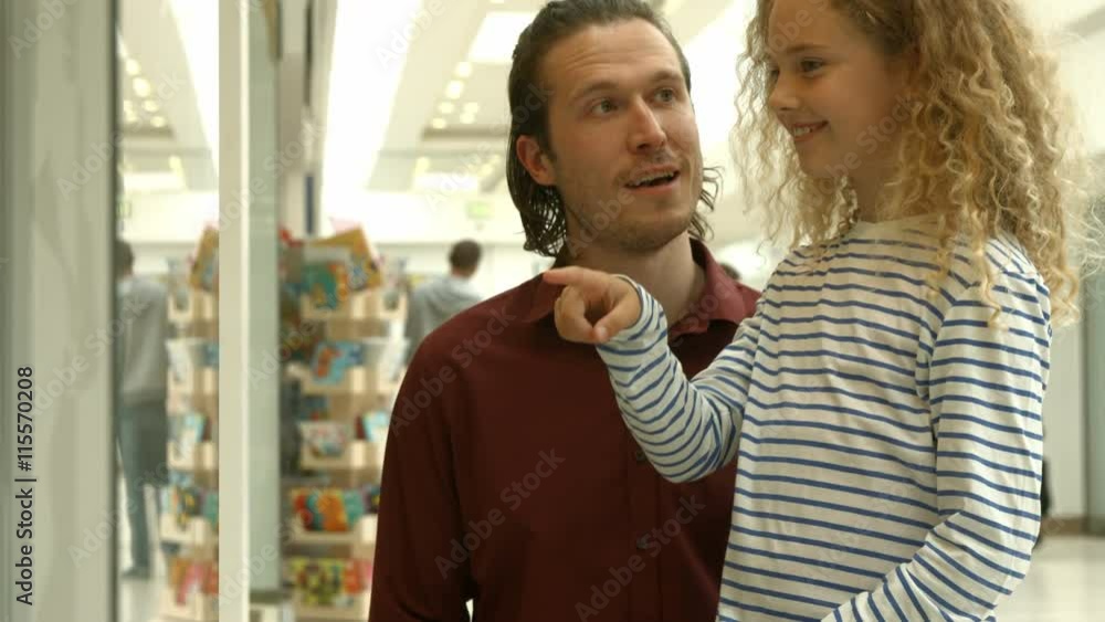 Father showing something to his daughter in shopping mall Father showing something to his daughter in shopping mall