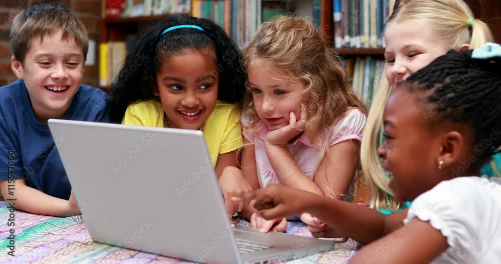 Pupils using the laptop together in the library in elementary school Pupils using the laptop together in the library in elementary school