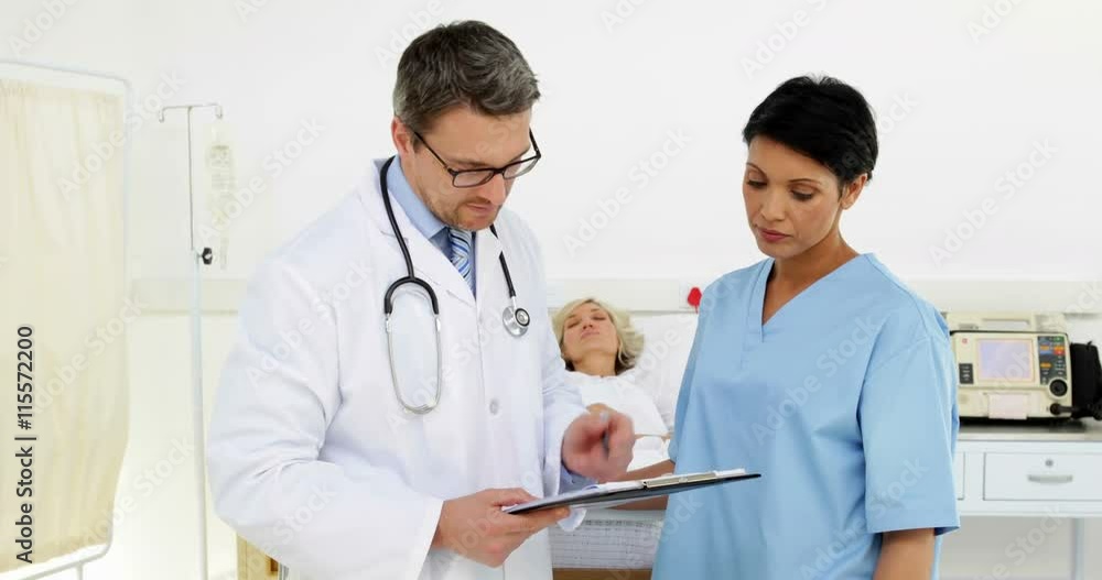 Doctors discussing patient as she sleeps in bed Doctors discussing patient as she sleeps in bed