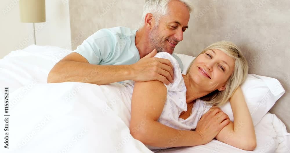 Couple lying in bed and smiling at camera Couple lying in bed and smiling at camera