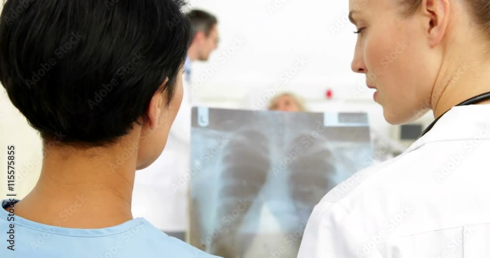 Doctors discussing xray in front of sick patient in bed Doctors discussing xray in front of sick patient in bed