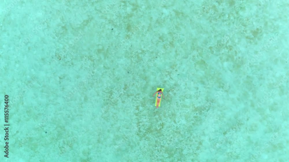 AERIAL: Flying above woman laying on inflatable air bed raft AERIAL: Flying above woman laying on inflatable air bed raft