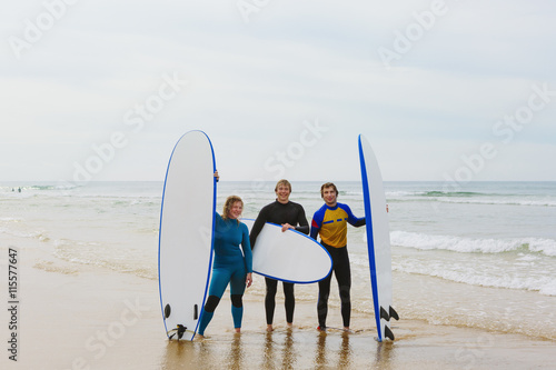 Portrait of smiling young people holding surfboards on beach