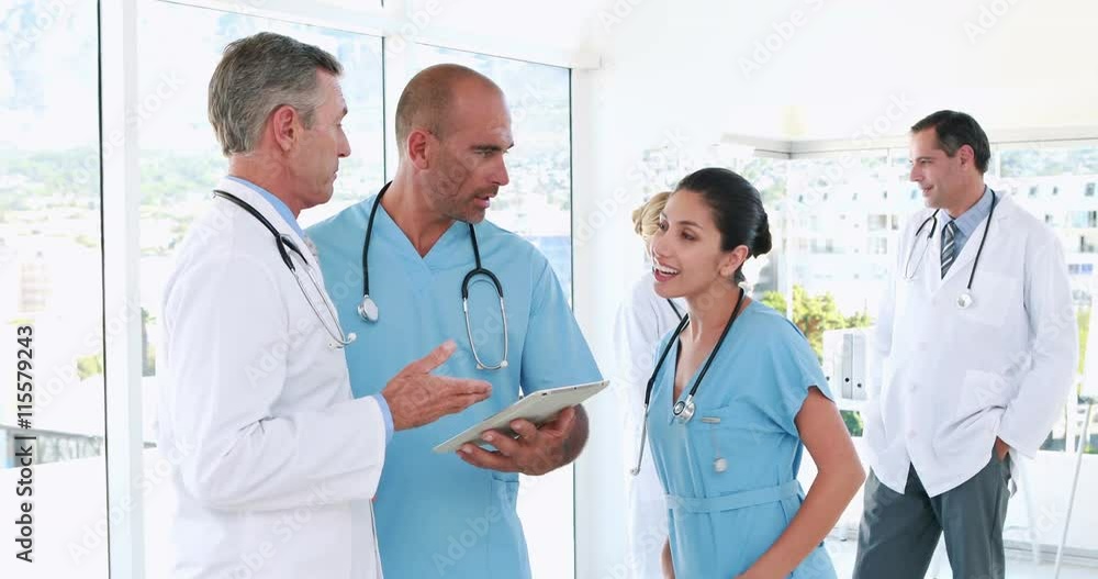 Video of medical team using tablet computer with their colleagues behind