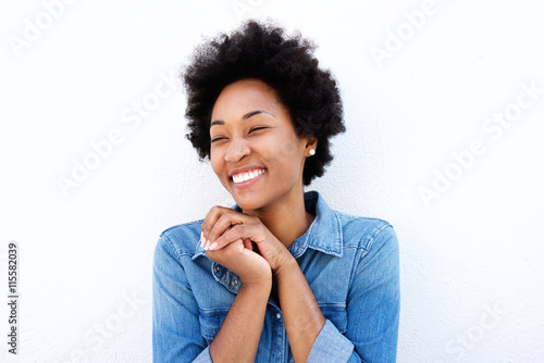 Delighted woman smiling by white wall