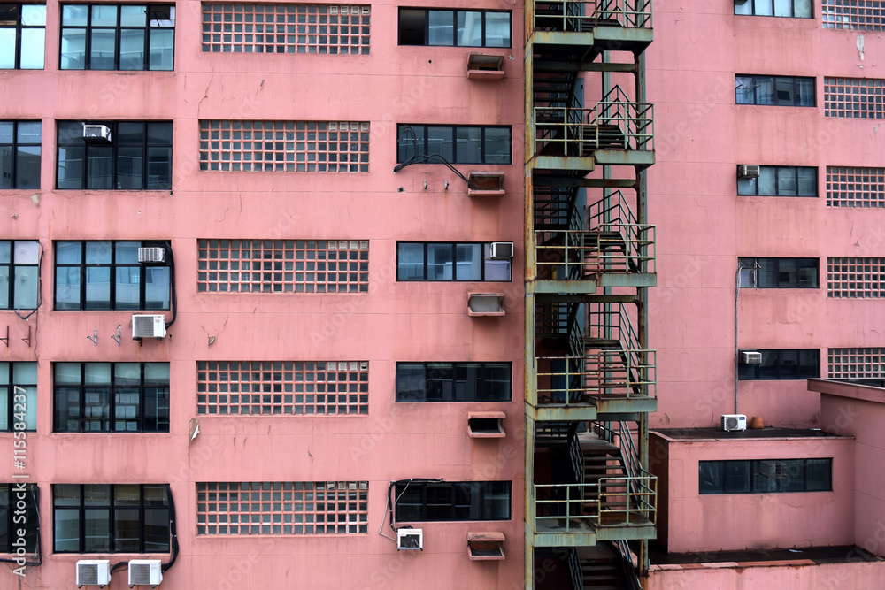 Side of dirty red apartment building with green stairs in Sao Paulo, Brazil
