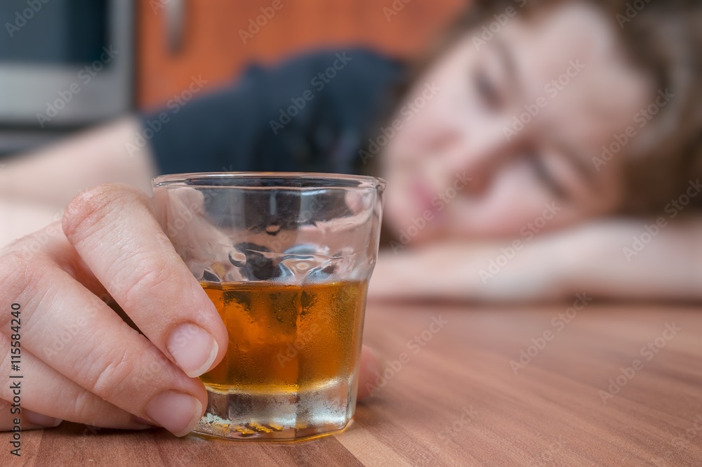 Alcoholic woman is sleeping on table. Glass with alcohol in hand. Alcoholic woman is sleeping on table. Glass with alcohol in hand.