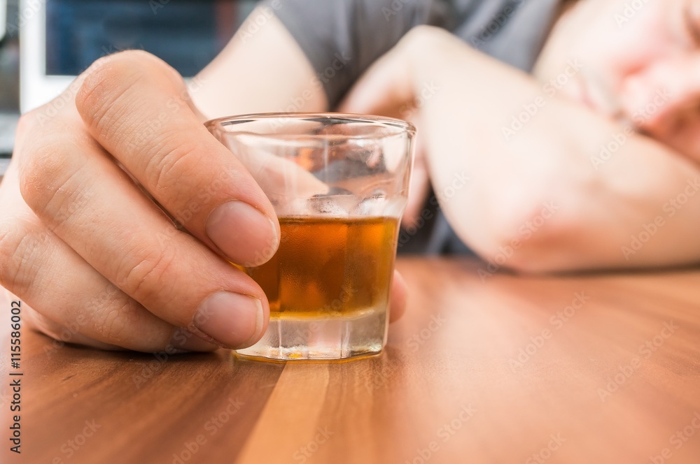 Alcoholic man is sleeping on table. Glass with alcohol in hand. Alcoholic man is sleeping on table. Glass with alcohol in hand.