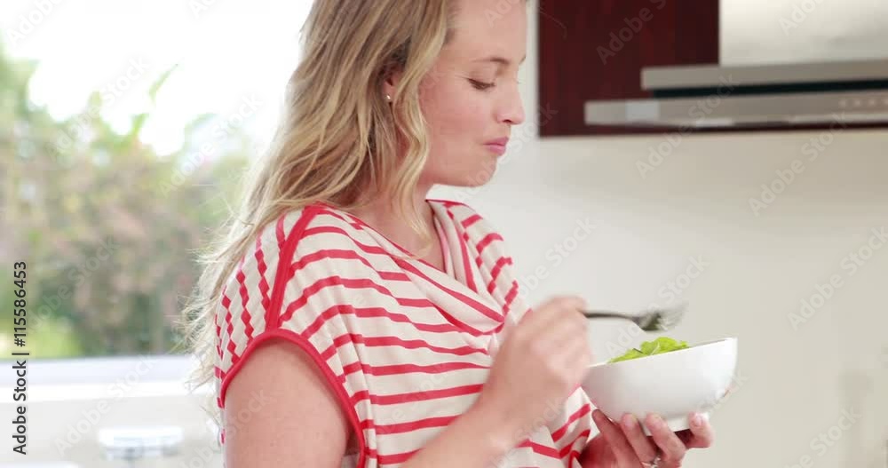 Pregnant woman eating salad in kitchen Pregnant woman eating salad in kitchen