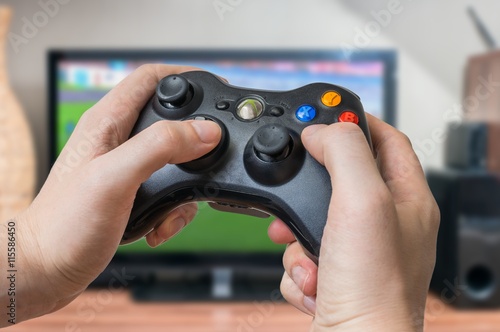 Young man is playing video games and holds joystick or controller. © vchalup