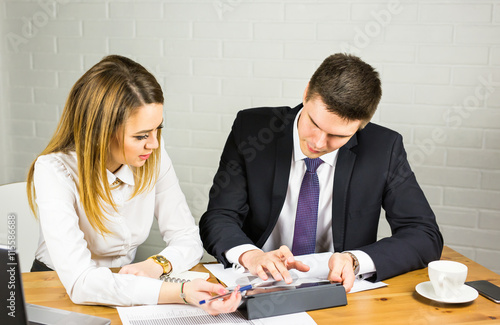 Two business people using tablet computer in office