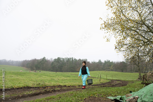 Sweden, Skane, Degeberga, Farmer carrying bucket photo