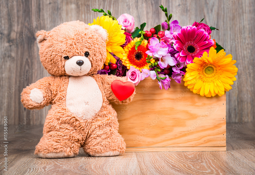 Obraz premium Beautiful flowers and a teddy bear on wooden background