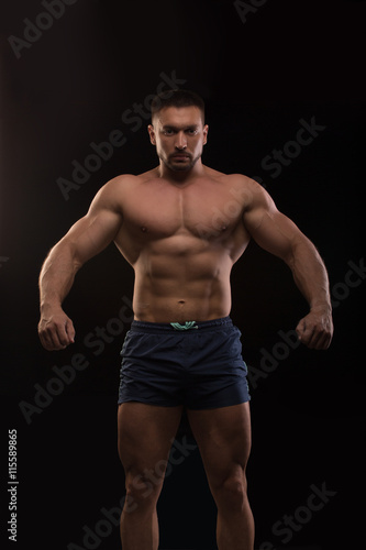 handsome muscular bodybuilder posing on a black background