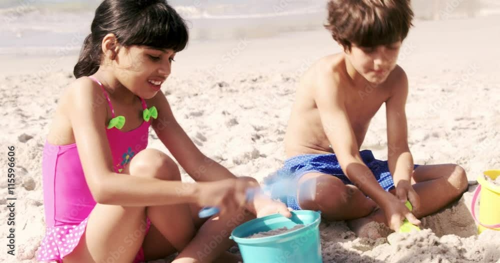 Cute siblings building a sand castle at the beach Cute siblings building a sand castle at the beach
