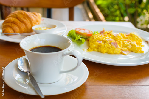 black coffee with croissant and scrambled eggs.
