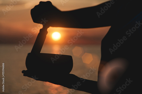 Obraz na płótnie Practice with singing bowl at the beach at sunset. Lens flare effect w salonie