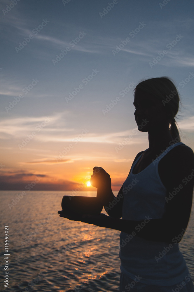 Practice with singing bowl at the beach at sunset