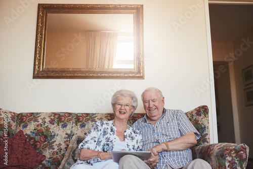 Smiling senior couple with a digital tablet at home