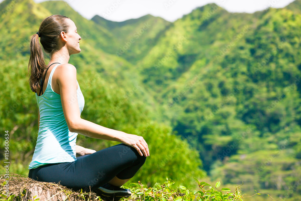 Happy woman meditating in a beautiful green setting. 
