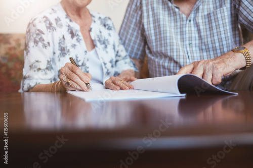 Senior woman signing documents with her husband photo