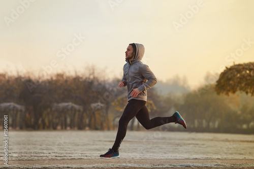 Young man running at park during winter, autumn morning